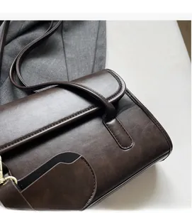 Close-up detail of dark brown vintage leather shoulder bag with smooth flap and fine stitching