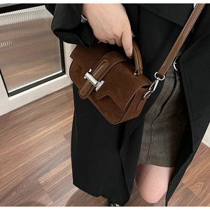 Détail du sac bandoulière en daim marron foncé avec poignée et boucle en métal argenté