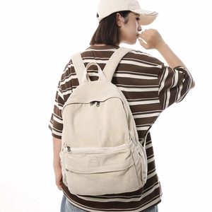 Cream corduroy backpack with multi-pocket design shown at a 45-degree angle on a model