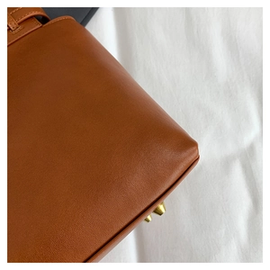 Detail of caramel leather tote bag corner with gold metal protective feet and pebble texture