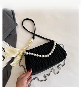 Detail of black velvet pleated bag with pearl handle and silk bow charm decoration