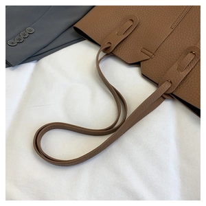 Détail du sac cabas en cuir marron avec coutures renforcées sur la bandoulière