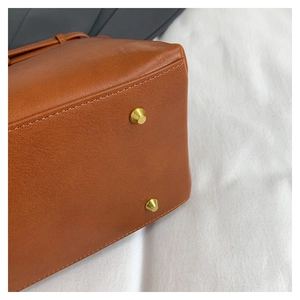 Detail shot of brown textured leather bag base with golden protective metal feet