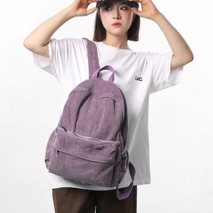 Purple corduroy backpack with large capacity and front zipper pocket on model