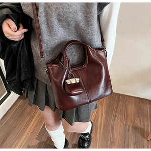 Dettaglio tote in pelle marrone scuro con charm portamonete e tracolla regolabile
