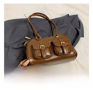 Detail of dark brown faux leather boston bag with dual front pockets and gold buckles