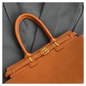 Detailed close-up of golden metal clasp and premium leather texture on a brown tote bag