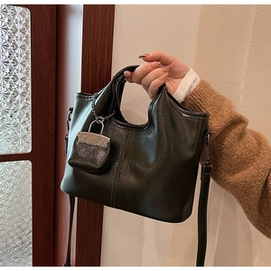 Dettaglio della borsa tote in pelle verde scuro con trama a grana e mini charm