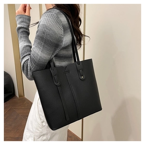 Sac fourre-tout en cuir litchi noir porté par un mannequin pour la taille et la forme