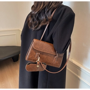 Detail view of brown vintage shoulder bag with matching mini pouch and long strap on model