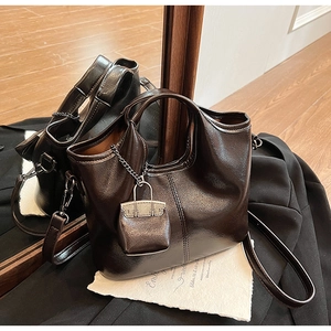 Dettaglio della pelle marrone lucida e del mini ciondolo coordinato su una borsa vintage