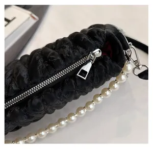 Close-up of smooth silver zipper and pearl strap on black pleated cloud shoulder bag