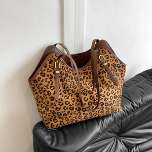 Grande borsa shopper leopardata con manici in pelle marrone su divano in pelle