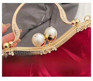 Detail of red velvet evening bag with gold clasp and large pearl sphere lock feature
