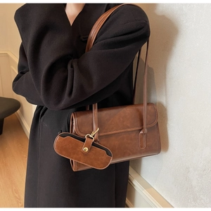 Close-up of vintage brown leather shoulder bag with a small detachable charm pouch