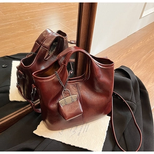 Dettaglio della borsa in pelle bordeaux con mini ciondolo e tracolla regolabile