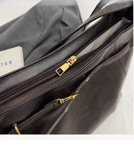 Detail of smooth gold metal zipper and premium brown PU leather on autumn tote bag