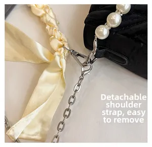 Detail of black quilted velvet bag with faux pearl handle and silver chain strap