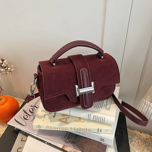 Sac à main carré bordeaux chic avec coutures en cuir et boucle argentée sur magazines