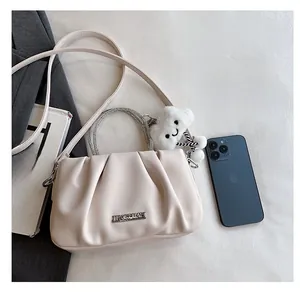 Dettaglio della borsa a nuvola pieghettata beige con catena di perle e ciondolo a nuvola