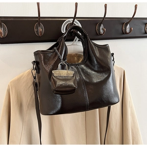 Dettaglio borsa a mano vintage marrone scuro con mini ciondolo coordinato e tracolla sottile