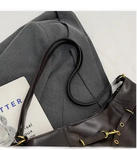 Close-up of vintage dark brown faux leather bag with aged gold hardware and side belt detail