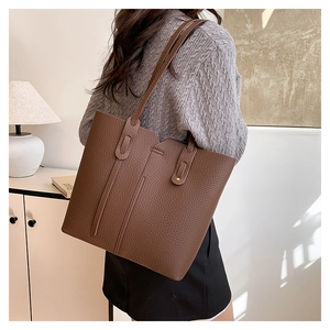 Détail du sac cabas en cuir marron grainé avec coutures verticales et bandoulière