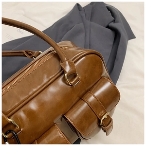 Detail of vintage caramel Boston bag with smooth leather texture and golden hardware