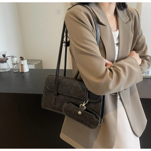 Detail of vintage suede shoulder bag with detachable mini pouch and gold clasp lock