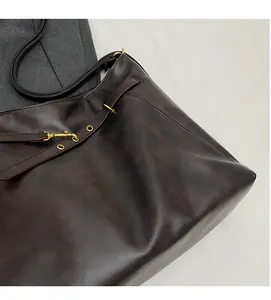 Detailed macro view of soft matte dark brown leather texture and stitching on tote bag
