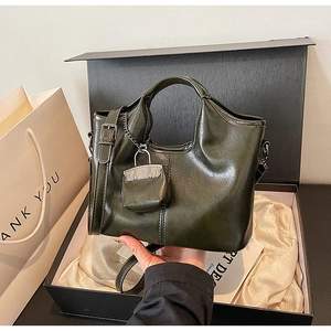 Vista dettagliata della borsa tote in pelle verde con ciondolo e confezione regalo di lusso