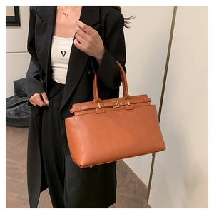 Detail of caramel brown tote bag featuring golden square buckle and matte leather texture