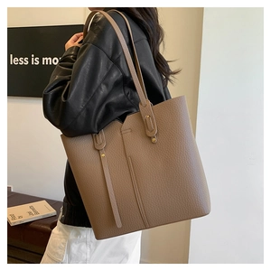 Détail de texture du cabas en cuir grainé marron avec couture asymétrique élégante