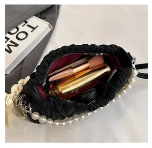 Macro view of black quilted bag interior with pearls, bow detail, and ample storage space