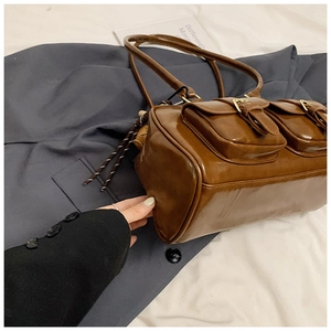 Close-up of vintage brown pillow bag with glossy finish and double front buckle pockets
