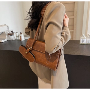 Detail view of a vintage brown shoulder bag with a small matching pouch in a cafe setting