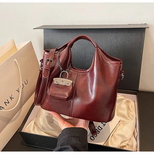 Dettaglio borsa tote rosso vino in pelle sintetica con mini ciondolo e tracolla rimovibile