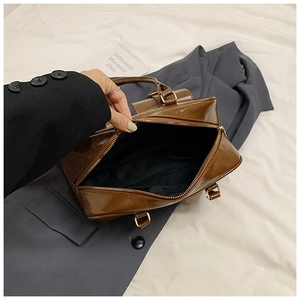 Detail view of large capacity dark brown leather bag with golden hardware and zipper