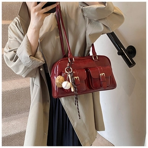 Close-up of glossy burgundy patent leather shoulder bag with vintage buckle pockets