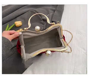 Detail of red velvet clutch bag with golden metal frame, large pearls, and inner lining