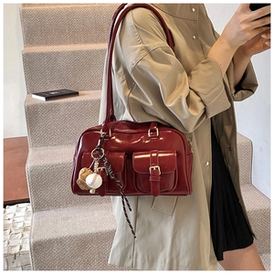 Deep red patent leather Boston bag detail featuring dual front pockets and baseball charm