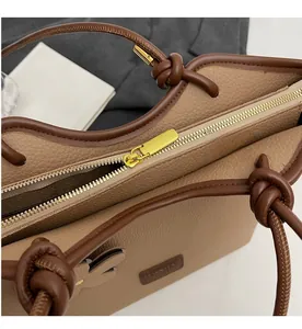 Detail of smooth gold zipper and pebble leather texture on khaki bucket bag
