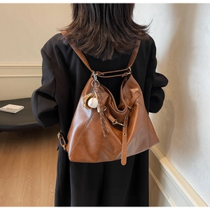 Detailed view of brown leather hobo bag with vintage texture and baseball glove charm