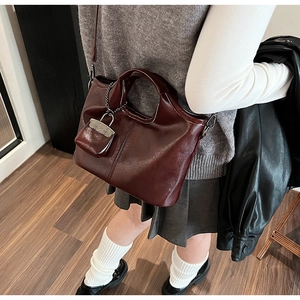 Dettaglio della borsa in ecopelle bordeaux con cuciture e ciondolo a mini borsa