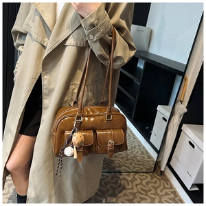 Close-up of vintage brown glossy leather handbag with pocket buckles and stylish charms