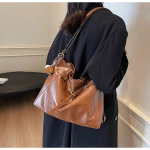Close-up of brown PU leather tote bag featuring heart pendant and metallic strap buckles
