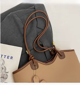 Close-up of the khaki bucket bag's durable handle with golden metal accents and heart charm