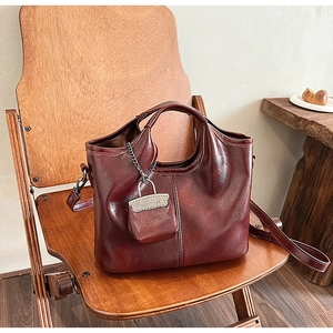 Dettaglio borsa bordeaux in ecopelle con mini pochette abbinata su sedia di legno