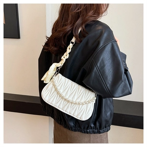 Detail of white ruched handbag featuring pearl chain and yellow silk scarf handle