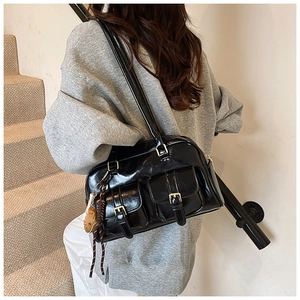 Detail view of black patent leather Boston bag featuring dual front flap pockets